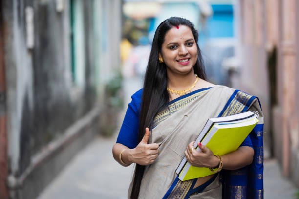istockphoto-1289489558-612x612 Outdoor image of Young Indian female School Teacher or College Professor holding books in hand.