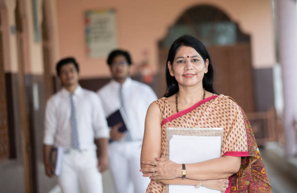 Confident smiling Indian school teacher with students in background Confident smiling Indian school teacher with students in background